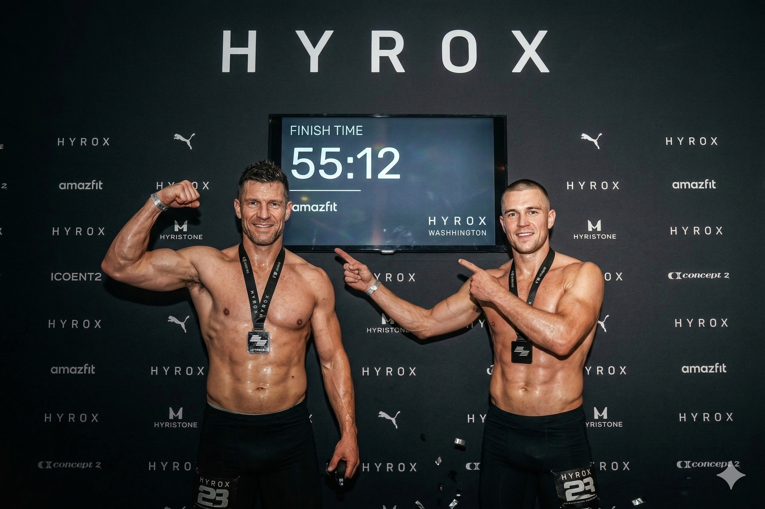 Two athletes celebrating in front of the HYROX race-finish board